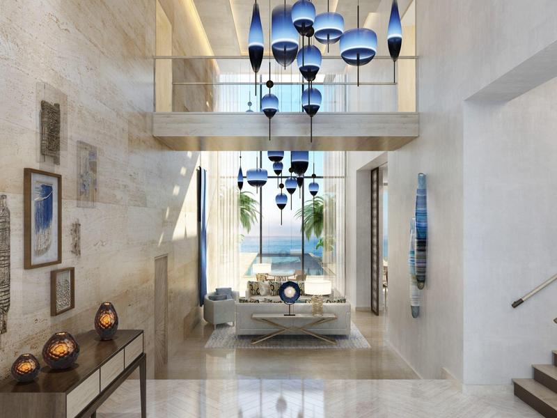Elegante hotelhal met moderne blauwe hanglampen en uitzicht op de zee.
