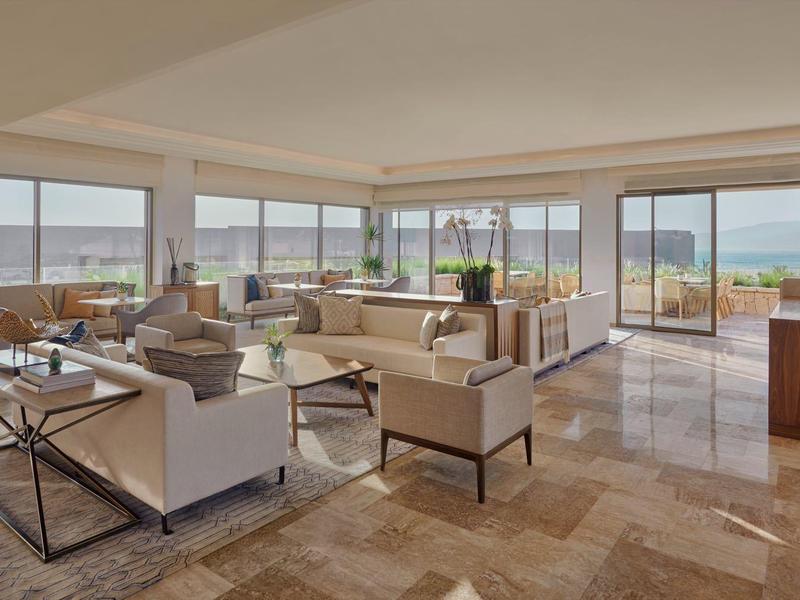 Licht gemeubileerde hotel lounge met grote ramen met uitzicht op het terras en de zee.