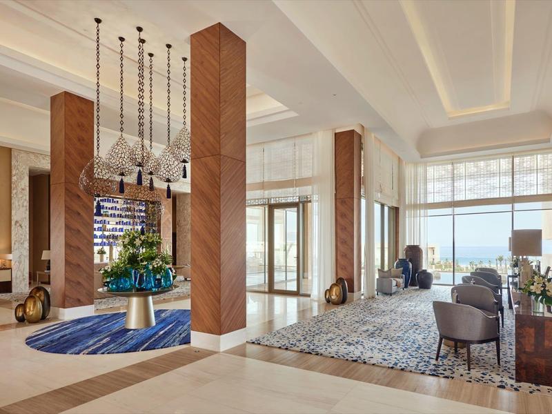 Ruime hotel lobby met moderne meubels, hoge plafonds en veel natuurlijk licht.