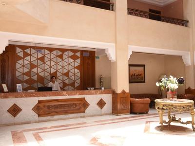 Helle Hotellobby mit Empfangstresen, dunklem Holzdekoration und Möbeln.