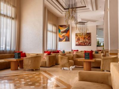 Heller, moderner Hotel-Loungebereich mit bequemen Sesseln und abstrakter Wandkunst.