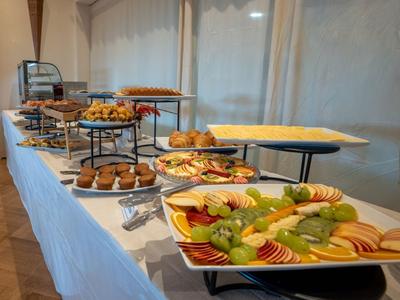 Buffet mit verschiedenen frisch geschnittenen Früchten und Gebäck auf einem weißen Tisch.