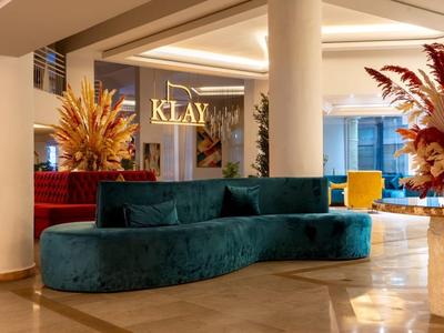 Moderner Hotel-Lobbybereich mit blaugrünem Sofa und dekorativen Pflanzenarrangements.