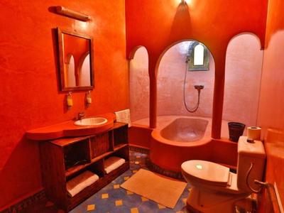 Bagno rosso con vasca da bagno incorporata, lavabo, WC e specchio.