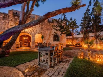 Accogliente area esterna di un hotel con sentiero in pietra rustico, alberi e illuminazione d'atmosfera al crepuscolo.