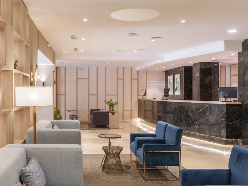 Moderner Empfangsbereich mit blauen Sitzsofas, grauen Sesseln, Holzwänden und schwarzem Marmor-Check-in.