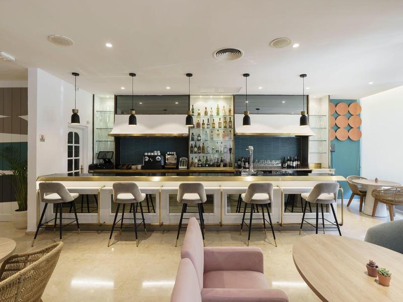 Moderner, heller Essbereich mit langem Theken-Tisch, Stühlen und minimalistischer Küchenausstattung.