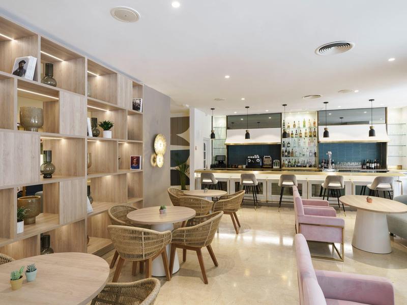 Moderner Café-Innenraum mit Holzregalen, runden Tischen, Stühlen und hellen Bodenfliesen.