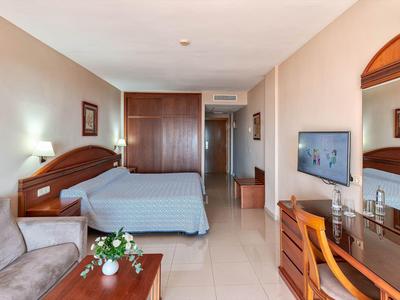 Gezellige hotelkamer met bed, bank, bureau en tv.