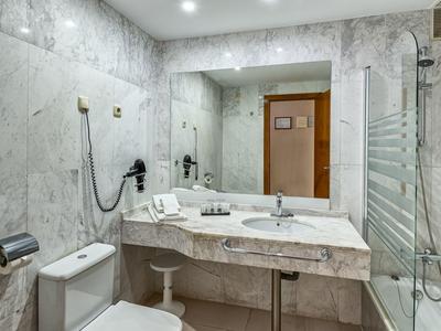 Elegant badkamer met marmeren wanden, wastafel, toilet en douche in een hotelkamer.