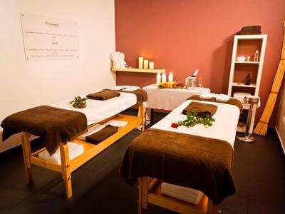 Gezellige massageruimte met twee tafels, warme tinten en een ontspannende sfeer.