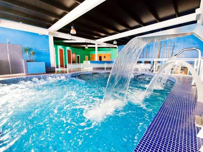 Overdekt zwembad met waterval en liggedeelte voor ontspanning tijdens verblijf.