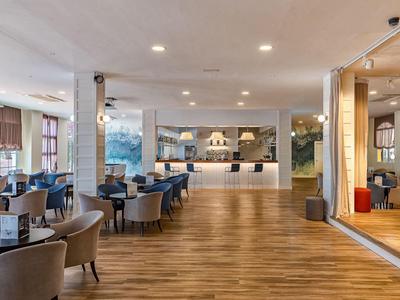 Heller, moderner Hotel-Lobby-Bereich mit Empfangstresen, Sitzgelegenheiten und Holzboden.