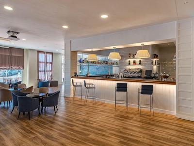 Moderner Hotelbarbereich mit Tresen, Sitzgelegenheiten und Holzboden.