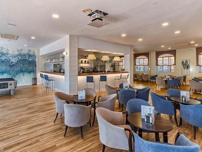 Moderne lounge met blauw-grijze stoelen, houten vloer en bar op de achtergrond.