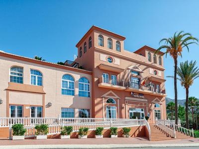 Een stijlvol hotel met terracotta verf en palmbomen onder een heldere blauwe hemel.