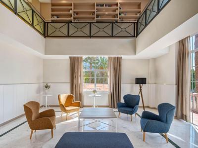 Lichte woonkamer met moderne meubels en grote ramen met uitzicht op een terras.