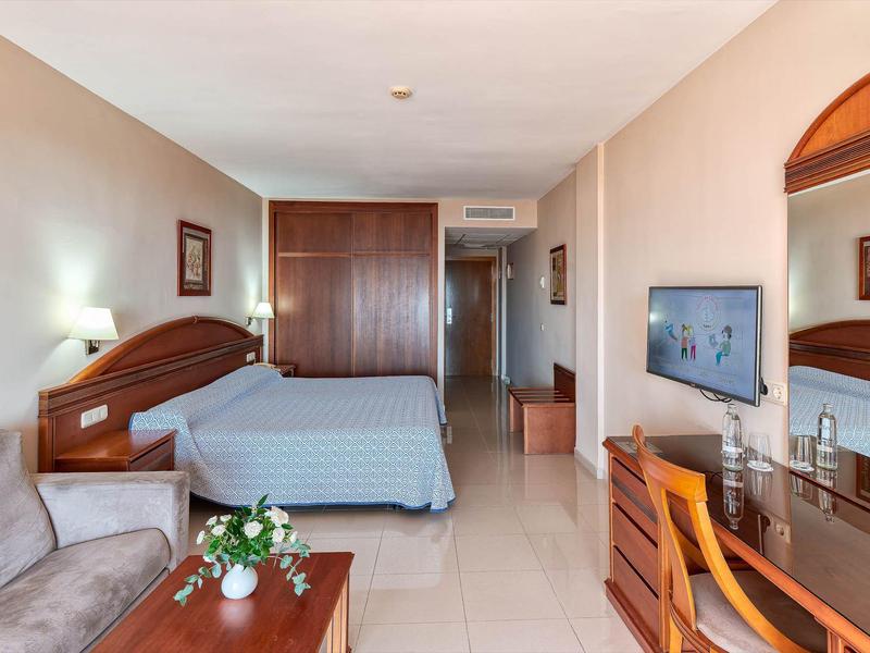 Gezellige hotelkamer met bed, bank, bureau en tv.