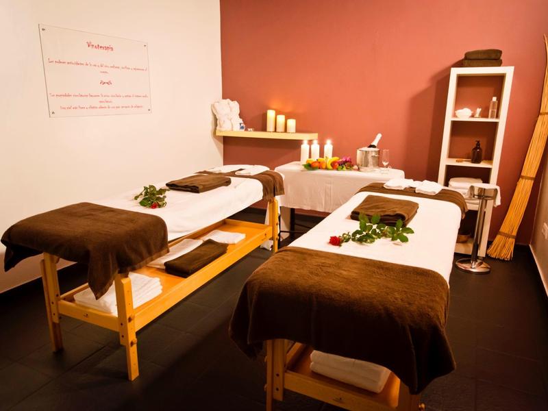 Gezellige massageruimte met twee tafels, warme tinten en een ontspannende sfeer.