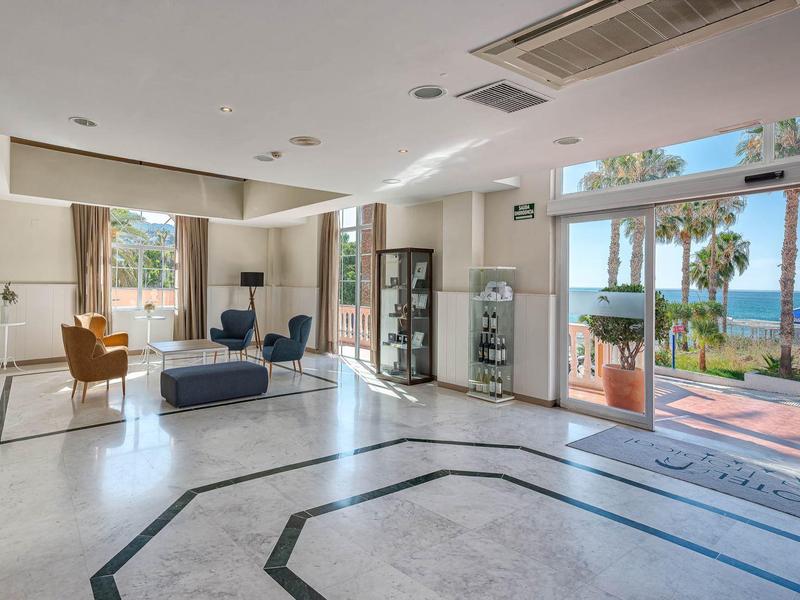 Lichte hotel lobby met comfortabele stoelen, marmeren vloer en uitzicht op de oceaan.