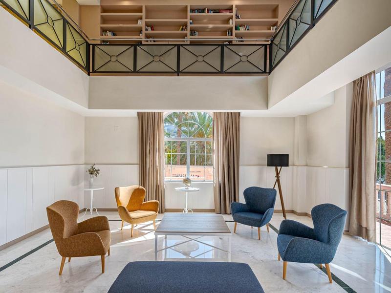 Lichte woonkamer met moderne meubels en grote ramen met uitzicht op een terras.