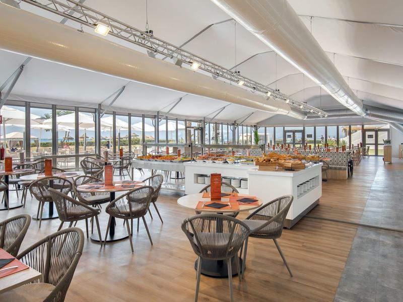 Ampio ristorante luminoso con tavoli in legno e grandi finestre panoramiche.