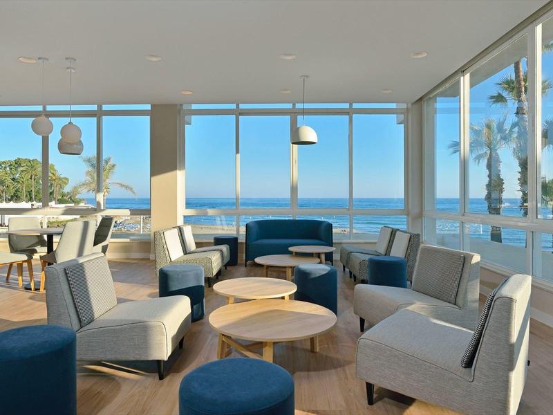 Salotto moderno con divani grigi e vista panoramica sul mare attraverso grandi finestre.