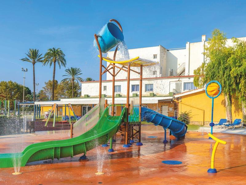 Area giochi acquatici con scivoli colorati in un complesso alberghiero soleggiato.