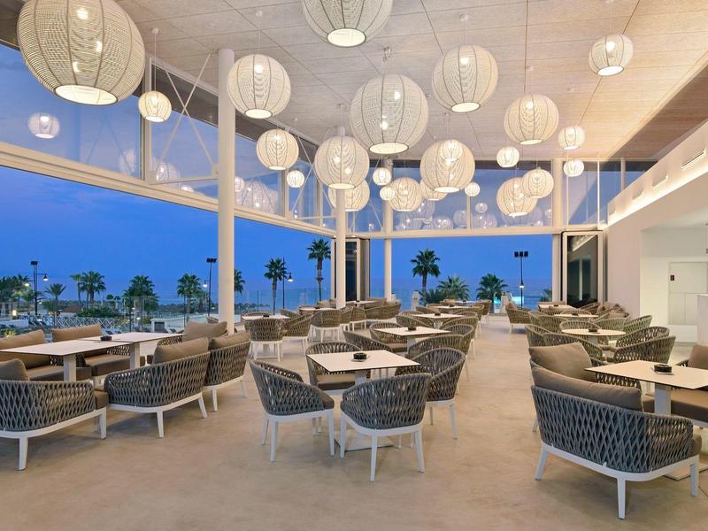 Terasa hotelové restaurace se sezením a zavěšenými světly za soumraku.