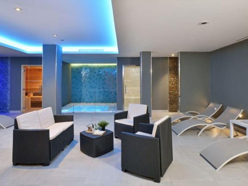 Moderní salón s černými křesly a lehátky v neonově osvětleném spa prostoru.