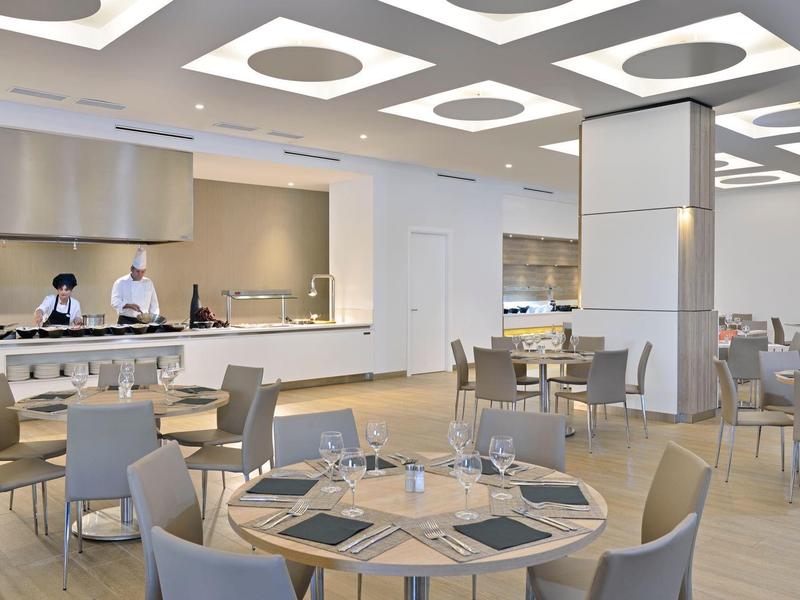 Moderní restaurace s prostřenými stoly a personálem viditelným v kuchyni.