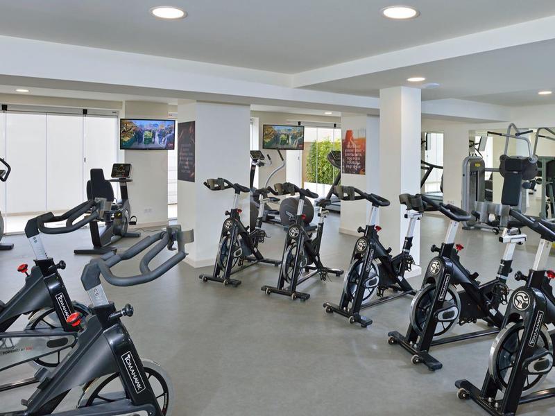 Salle de sport avec vélos d'appartement alignés dans un espace lumineux et moderne.