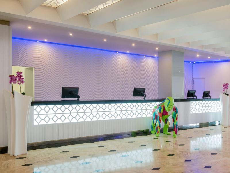 Réception d'hôtel moderne avec écran lumineux et décoration colorée d'éléphant.