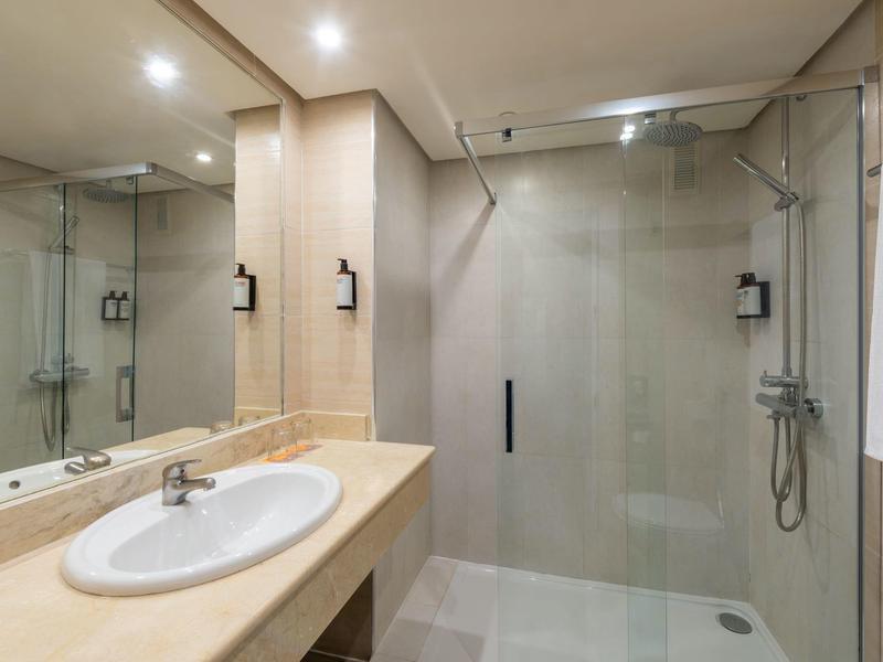 Salle de bain avec douche vitrée et lavabo contemporain en marbre beige.
