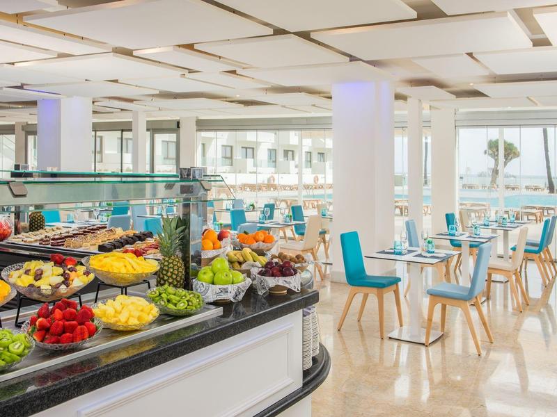 Buffet coloré de fruits frais dans un restaurant lumineux avec vue sur la mer.