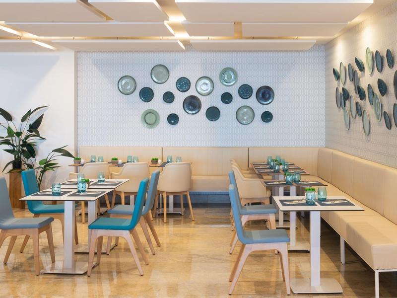 Salle à manger d'hôtel avec chaises bleues et décorations murales circulaires.