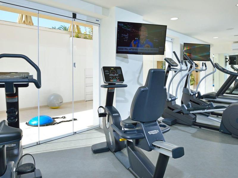 Salle de sport lumineuse avec vélos d'appartement et tapis roulants modernes.