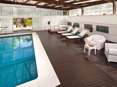 Piscina cubierta con tumbonas y muebles cómodos en una sala de diseño moderno.