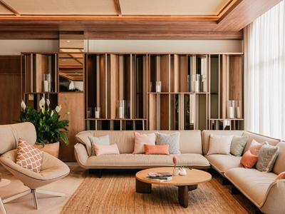 Moderne woonkamer met beige banken, houten planken en grote ramen met witte gordijnen.