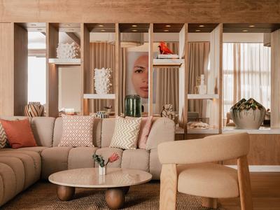 Gezellige hotellounge met beige bank, ronde tafel en warme decoraties bij daglicht.