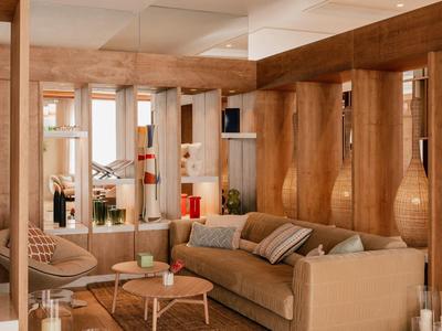 Lichte woonkamer met beige bank, houten wandpanelen en grote wandspiegel.