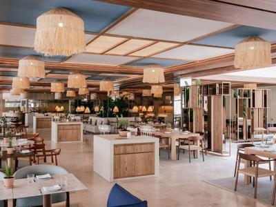 Modern eingerichteter Hotelrestaurantbereich mit Tischen, Stühlen und dekorativen Lampen.