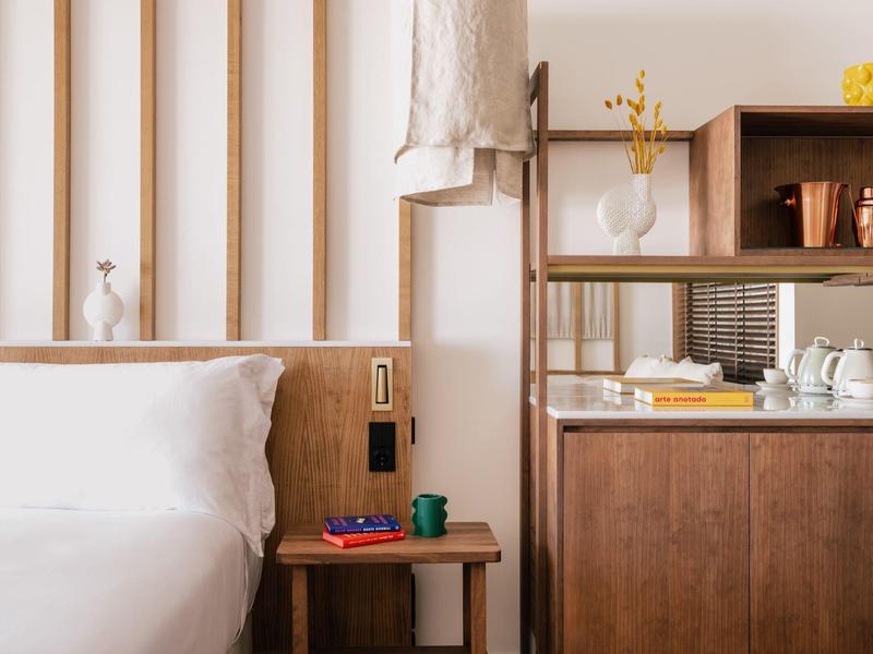 Moderne hotelkamer met wit bed, houten wandbekleding en decoratieve dressoir.