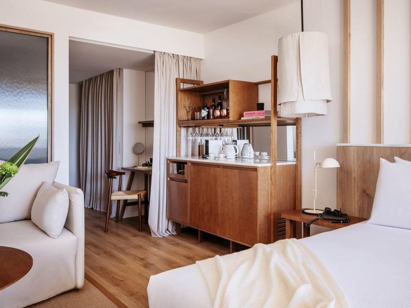 Modern hotelkamer met houten vloer, gezellig bed en stijlvol zithoekje.