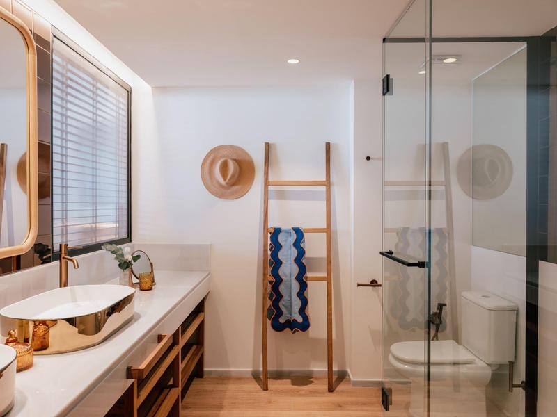 Moderne badkamer met witte wastafel, houten accenten en een ladder als handdoekhouder.