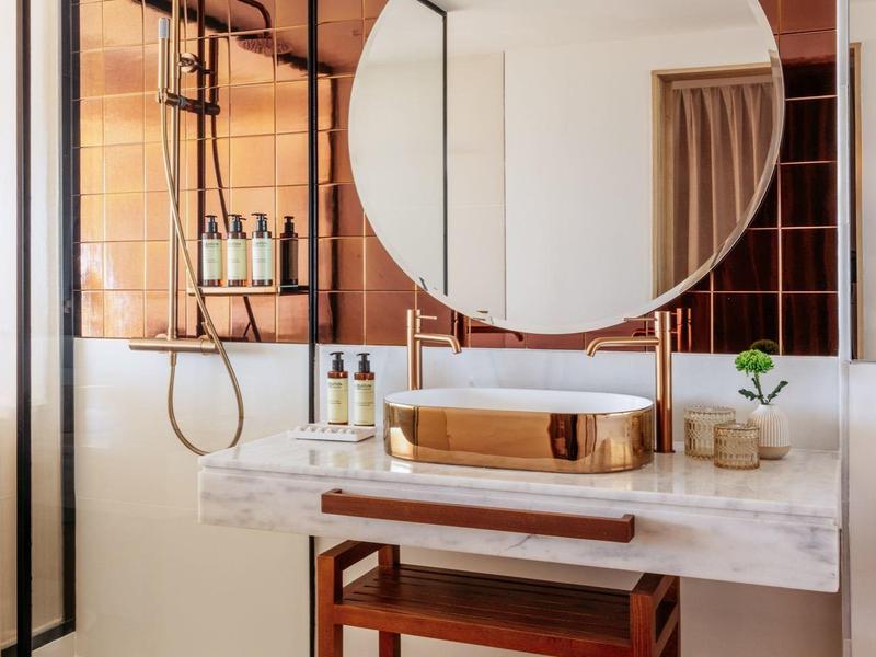 Moderne badkamer met ronde wandspiegel, houten wastafel en inloopdouche achter glazen wand.