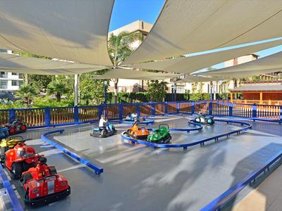 Elektrické motokáry na venkovní dráze se slunečními stínícími plachtami v hotelové oblasti.