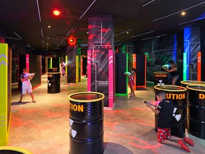 Innenaufnahme einer Laser-Tag-Arena mit leuchtenden Hindernissen und Spielern in Schutzkleidung.