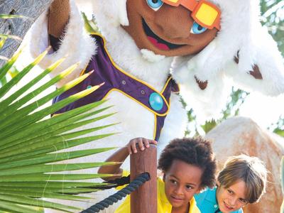 Šťastné děti pózují s postavou v kostýmu venku.