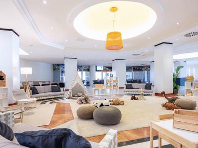 Světlý moderní hotelový salonek s útulnými posezeními a měkkými koberci.